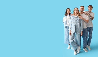 Group of young people in stylish jeans on light blue background with space for text