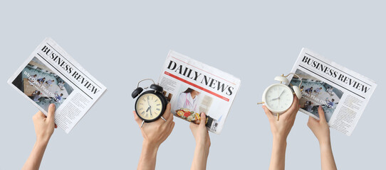 Hands holding different alarm clocks and newspapers on grey background