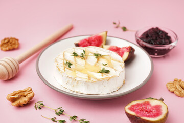 Plate of tasty baked Camembert cheese on pink background