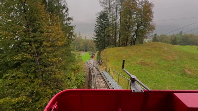 Beautiful POV ride on the historic Reichenbachfall-Bahn funicular in the Swiss Alps. Experience stunning alpine views as the vintage wooden carriage ascends towards the iconic Reichenbach Falls