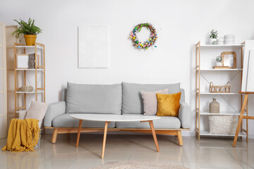 Interior of living room with Easter wreath, shelf units and sofa