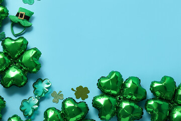 Balloons in shape of clover and decorations for St. Patrick's Day celebration on blue background
