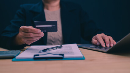 A woman is holding a credit card and typing on a laptop. Concept of financial responsibility and organization
