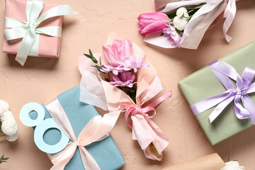 Mini bouquets of beautiful spring flowers in wrapping paper with gift boxes and figure 8 on beige background. International Women's Day