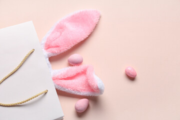 Shopping bag with fluffy bunny ears and Easter eggs on beige background