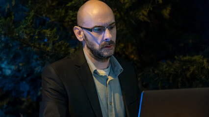 A middle-aged handsome businessman in a suit working with his laptop outside the office...