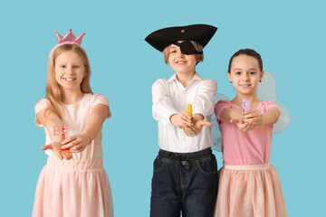 Cute little kids in festive costumes with graggers on blue background. Purim celebration