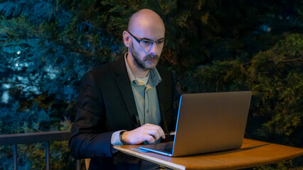A middle-aged handsome businessman in a suit working with his laptop outside the office...