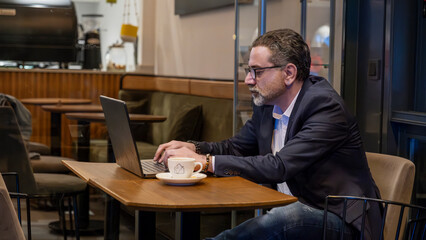 Mature handsome businessman in suit working with laptop outside office environment with full focus