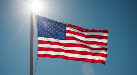 Fototapeta premium American Flag Waving Proudly Against a Clear Blue Sky with Sun