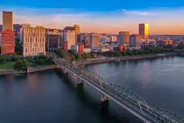 Naklejka premium Portland, Oregon skyline at sunset, with the Hawthorne Bridge spanning the Willamette River. Cityscape, bridge, and golden hour light. Hawthorne Bridge, Oregon, USA
