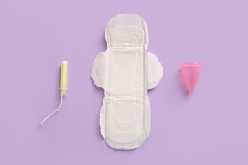 Menstrual pad with tampon and cup on purple background