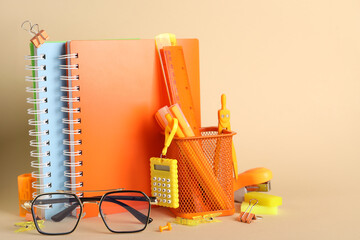 Eyeglasses and school supplies on beige background