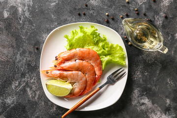 Plate with tasty boiled shrimps, lettuce and lime on dark background