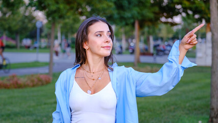 A young, beautiful brown-haired businesswoman is pointing to a corner of the screen with her index...