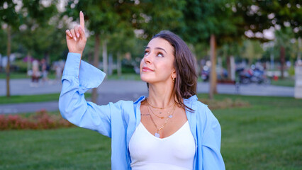 A young, beautiful brown-haired businesswoman is pointing to a corner of the screen with her index...