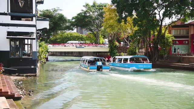 Malacca, Malaysia - December 29, 2019: Tourist boats floating on the tranquil waters of Malacca River with city views
