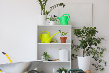 Obraz premium Set of gardening tools and plants near light wall