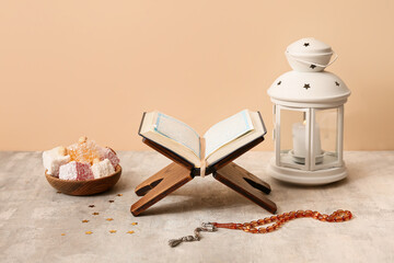 Koran, prayer beads, Turkish delight and lantern on grey table against beige background. Ramadan...