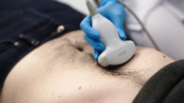 Ultrasound diagnosis of abdominal organs for a man in the clinic. The doctor moves the ultrasound probe on the patient's abdomen. Concept of advanced medical technology for accurate diagnosis.