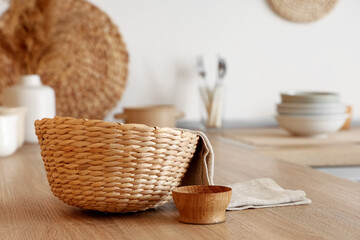 Bowl, napkin and wicker basket on wooden table in kitchen, closeup