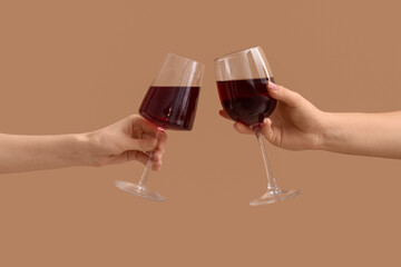 Female hands with glasses of red wine on beige background
