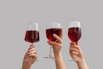 Female hands with glasses of red wine on white background