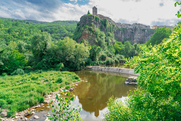 Pueblo medieval en las montañas sobre un acantilado de roca y mucha vegetación un día soleado...