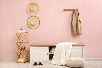 Stand for shoes and bench near pink wall in interior of hallway