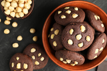 Tasty chocolate cookies with hazelnuts on black table, flat lay