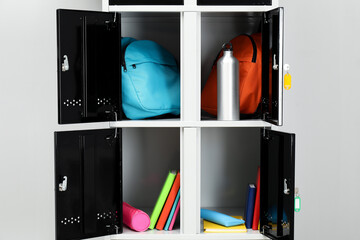 Lockers with school supplies on light background