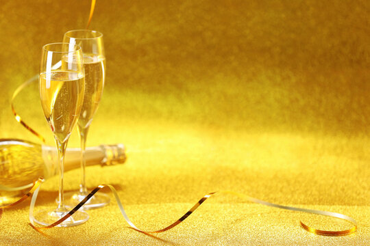 Champagne in glasses and bottle on golden background. Space for text - Powered by Adobe