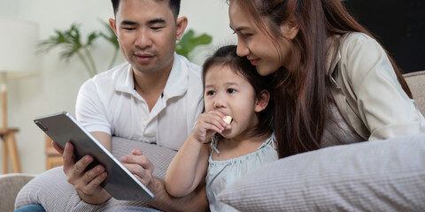 Family sharing a tablet while enjoying snacks and bonding together.
