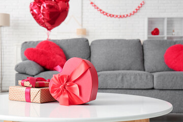 Table with heart-shaped gift boxes in stylish living room, closeup. Valentine's Day celebration