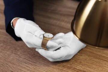 Appraiser with luxury wristwatch at wooden table, closeup