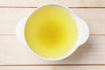 Tasty chicken bouillon in bowl on wooden table, top view
