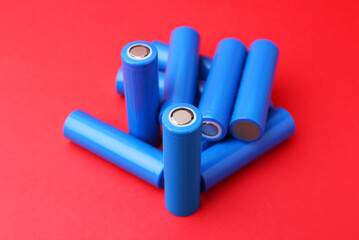 Many AA cell batteries on red background, closeup
