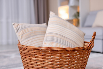 Wicker basket with pillows in living room, closeup