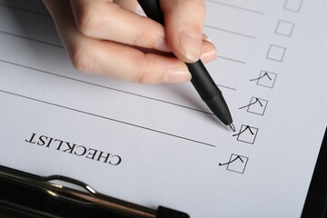 Woman filling Checklist with pen, above view