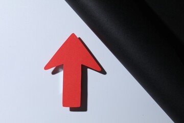 One red paper arrow on color background, top view