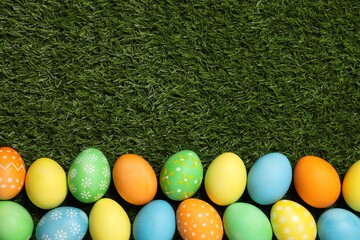 Beautiful decorated Easter eggs on green grass, flat lay. Space for text