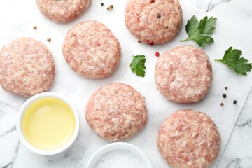 Many uncooked patties and spices on white marble table, flat lay