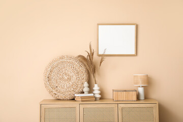Interior of living room with chest of drawers near beige wall