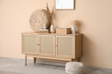 Interior of living room with chest of drawers near beige wall
