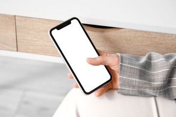 Young businesswoman holding blank mobile phone in office, closeup
