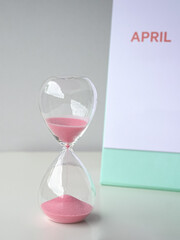 Sand timer next to April calendar. Copy space.