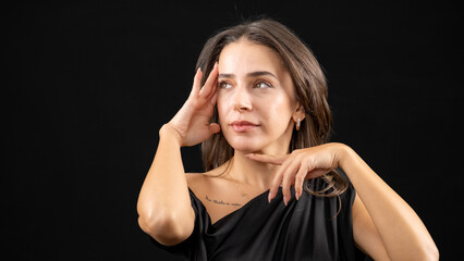 A chest-up headshot of a young, brown-haired woman taken in a studio setting with a black background