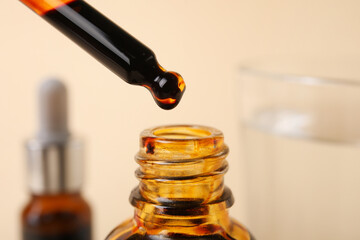 Bottle with iodine and pipette on beige background, closeup