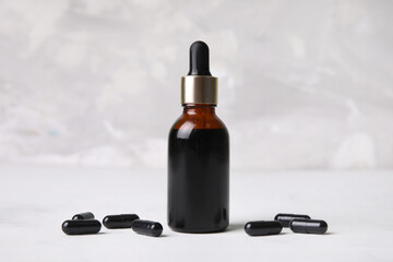 Bottle with iodine and black pills on grey grunge background, closeup