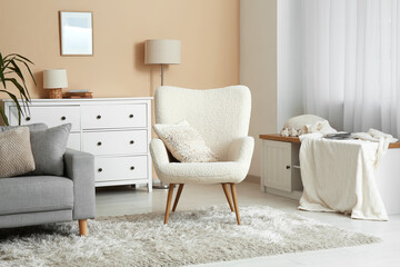 Interior of light living room with armchair and sofa near beige wall
